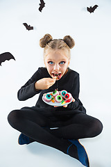 Image showing Little girl witch in black dress over magical accessories. Halloween, the studio evening.