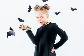 Image showing Little girl witch in black dress over magical accessories. Halloween, the studio evening.