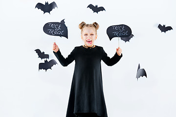 Image showing Little girl witch in black dress over magical accessories. Halloween, the studio evening.