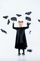 Image showing Little girl witch in black dress over magical accessories. Halloween, the studio evening.