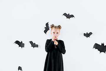 Image showing Little girl witch in black dress over magical accessories. Halloween, the studio evening.