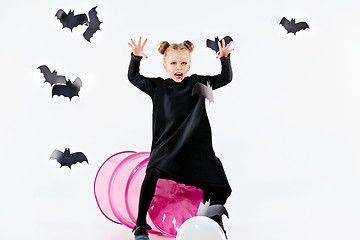 Image showing Little girl witch in black dress over magical accessories. Halloween, the studio evening.