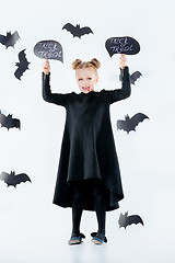 Image showing Little girl witch in black dress over magical accessories. Halloween, the studio evening.