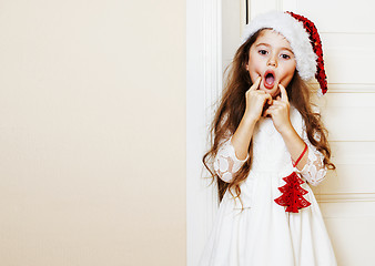 Image showing little cute girl in santas red hat waiting for Christmas gifts. 