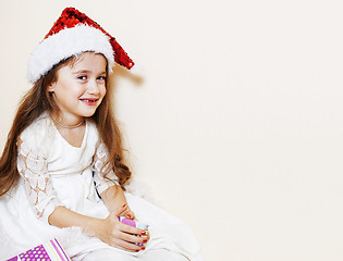 Image showing little cute girl in santas red hat waiting for Christmas gifts. 