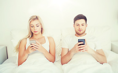 Image showing couple with smartphones in bed