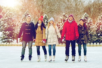 Image showing happy friends ice skating on rink outdoors