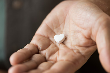 Image showing close up of hand with heart shaped pill