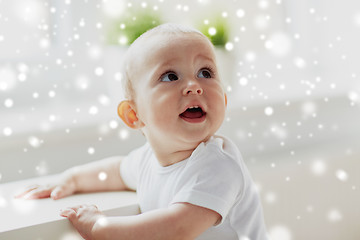 Image showing happy little baby boy or girl holding to table