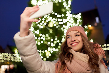 Image showing young woman taking selfie over christmas tree