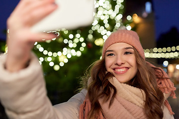 Image showing young woman taking selfie over christmas tree