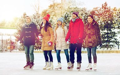 Image showing happy friends ice skating on rink outdoors