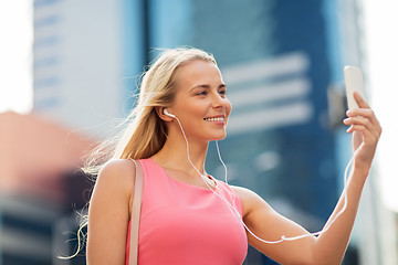 Image showing happy young woman with smartphone and earphones