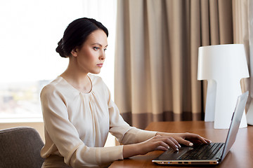 Image showing businesswoman typing on laptop at hotel room