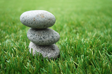 Image showing Pebbles stacked up on grass