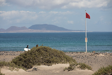 Image showing The red flag weighs in the wind at Surfers Beach Famara on Lanza