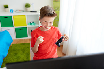 Image showing boy with gamepad playing video game on computer