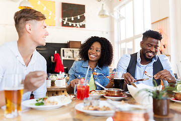 Image showing happy friends eating and talking at restaurant