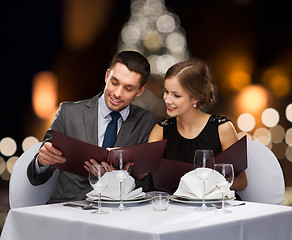 Image showing smiling couple with menus at christmas restaurant