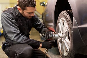 Image showing auto mechanic with screwdriver changing car tire