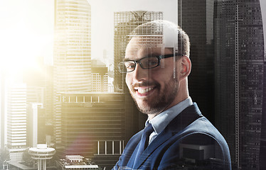 Image showing smiling businessman in glasses over city buildings