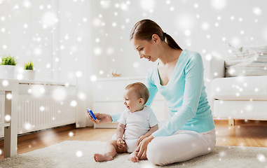 Image showing happy mother showing smartphone to baby at home