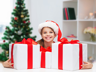 Image showing smiling girl in santa hat with christmas gifts