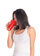 Image showing Hispanic woman drinking from a red mug.