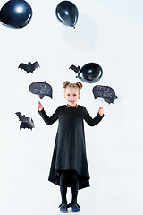 Image showing Little girl witch in black dress over magical accessories. Halloween, the studio evening.