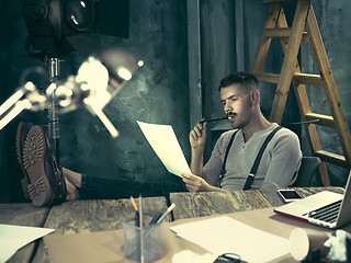 Image showing Portrait of a bearded businessman who is working with his notebook at loft studio.