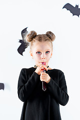 Image showing Little girl witch in black dress over magical accessories. Halloween, the studio evening.