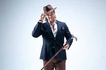 Image showing The mature man in a suit and hat holding cane.