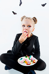 Image showing Little girl witch in black dress over magical accessories. Halloween, the studio evening.