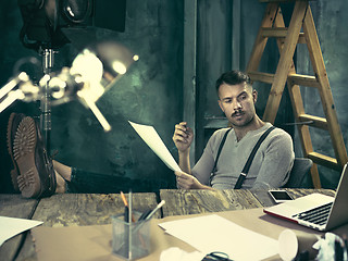 Image showing Portrait of a bearded businessman who is working with his notebook at loft studio.