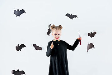 Image showing Little girl witch in black dress over magical accessories. Halloween, the studio evening.