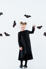 Image showing Little girl witch in black dress over magical accessories. Halloween, the studio evening.