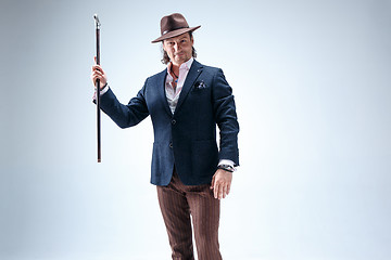 Image showing The mature man in a suit and hat holding cane.