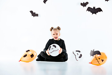 Image showing Little girl witch in black dress over magical accessories. Halloween, the studio evening.