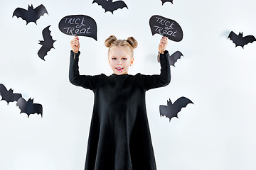 Image showing Little girl witch in black dress over magical accessories. Halloween, the studio evening.