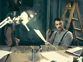 Image showing Portrait of a bearded businessman who is working with his notebook at loft studio.