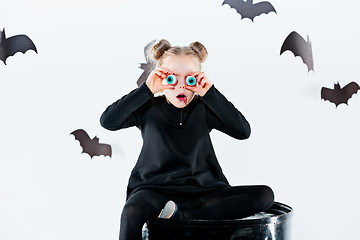 Image showing Little girl witch in black dress over magical accessories. Halloween, the studio evening.