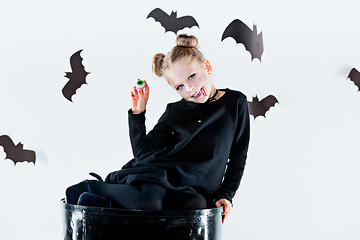 Image showing Little girl witch in black dress over magical accessories. Halloween, the studio evening.