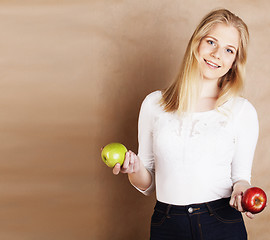 Image showing young pretty blond woman with green apple happy cheerful smiling close up on warm brown background, lifestyle real people concept