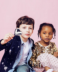 Image showing lifestyle people concept: diverse nation children playing together, caucasian boy with african little girl holding candy happy smiling 