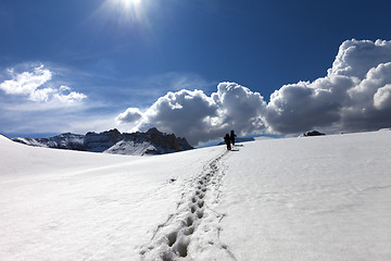 Image showing Footpath in snow and two hikers on snowy plateau at sun spring d