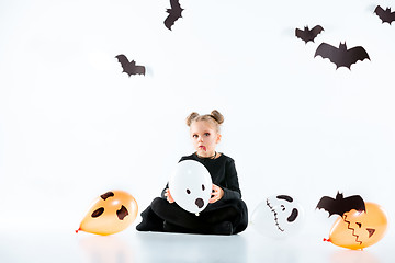 Image showing Little girl witch in black dress over magical accessories. Halloween, the studio evening.