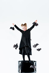 Image showing Little girl witch in black dress over magical accessories. Halloween, the studio evening.