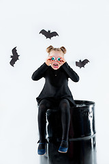 Image showing Little girl witch in black dress over magical accessories. Halloween, the studio evening.