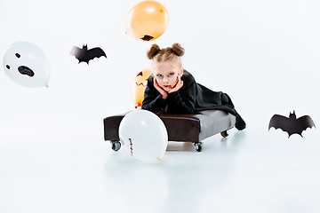 Image showing Little girl witch in black dress over magical accessories. Halloween, the studio evening.