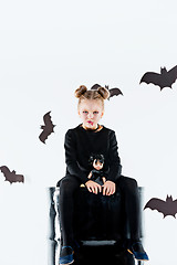 Image showing Little girl witch in black dress over magical accessories. Halloween, the studio evening.